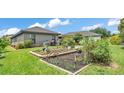 A large backyard featuring green grass, a garden, and a patio area with a grill at 364 Lake Vista Dr, Auburndale, FL 33823