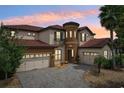 Beautiful two-story home with a circular tower, three-car garage, and a gorgeous tiled roof at sunset at 3833 Bowfin Trl, Kissimmee, FL 34746