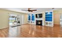 Bright living room with wood floors, built-in shelves, fireplace, and sliding doors to the screened pool area at 419 Broward Ter, Winter Haven, FL 33884