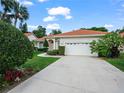 Inviting single-story house featuring a tile roof, white stucco, a two-car garage, and well-maintained landscaping at 530 Greenway Dr, Lake Wales, FL 33898