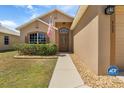 Inviting front entrance with a decorative door, an American flag, and lush landscaping at 533 Ronshelle Ave, Haines City, FL 33844