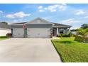 Beautiful single-story home featuring a three-car garage, an American flag, and manicured landscaping at 1045 Montgomery Ln, Polk City, FL 33868