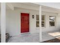 Close-up of the front porch, featuring a vibrant red door flanked by windows and a well-lit exterior at 1103 W Dixie Ave, Plant City, FL 33563