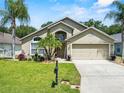 Charming single Gathering home featuring lush landscaping, mature palm trees, and a driveway at 1357 Rebecca Dr, Haines City, FL 33844