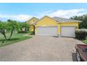 Bright yellow home featuring a paved driveway leading to a two-car garage and lush green lawn at 147 Brookshire Dr, Lake Wales, FL 33898