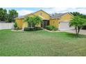 Inviting yellow home with manicured lawn, palm trees, and a charming entrance at 147 Brookshire Dr, Lake Wales, FL 33898