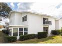 White condo featuring a screened patio, a small balcony and manicured landscaping at 1550 11Th Ne St # E7, Winter Haven, FL 33881