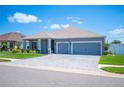 Beautiful single-story home showcasing a paver driveway, lush landscaping, and a classic design under a sunny sky at 157 Walkers Point Dr, Auburndale, FL 33823