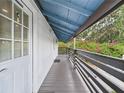 Covered outdoor walkway with gray wood railing, white walls, and a painted blue ceiling at 2222 12Th Nw St, Winter Haven, FL 33881