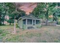 Charming, green cottage-style home with a screened-in porch and mature trees at 230 Denton Ave, Auburndale, FL 33823
