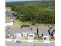 Aerial view of a home with a brick driveway, red shutters and a nearby pond surrounded by lush greenery at 2356 Palm Park Loop, Clermont, FL 34714
