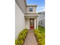 Inviting front entrance with a red door, brick pathway, and vibrant yellow landscaping at 2356 Palm Park Loop, Clermont, FL 34714