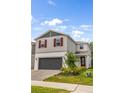 Beautiful two-story home featuring gray siding, a brick driveway, red shutters, and neatly arranged landscaping at 2356 Palm Park Loop, Clermont, FL 34714