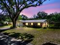 Dusk view of the brick home with a metal roof and a well manicured lawn at 2640 Handley Blvd, Lakeland, FL 33803