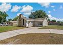 Well-manicured front yard of a charming single-story house with a stone chimney and a concrete driveway at 3022 Lantana Rd, Auburndale, FL 33823