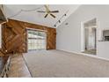 Spacious living room featuring unique wooden walls, cozy carpet, ceiling fan, and sliding glass doors at 3022 Lantana Rd, Auburndale, FL 33823