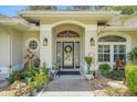 Inviting front entrance featuring decorative plants, a modern front door with sidelights, and stylish outdoor lighting at 3158 Beauchamp Ct, Winter Haven, FL 33884