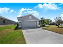 Gray house in a quiet neighborhood features a two-car garage, well-maintained lawn, and tropical landscaping at 3374 Waterlute Way, Lakeland, FL 33811