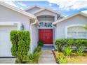 Close up of a front entrance featuring a red double-door, manicured landscaping, and an arched transom window at 799 Highland Crest Loop, Lake Wales, FL 33853
