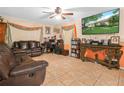 Cozy living room featuring tile flooring, a ceiling fan, a leather sofa, and a mounted television at 808 Ware Ne Ave, Winter Haven, FL 33881