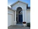 Charming home featuring an arched entryway with a blue front door and white columns at 135 Minniehaha Cir, Haines City, FL 33844