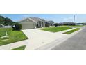 Expansive front yard showcasing a lush green lawn, featuring a long driveway leading to an attached two-car garage at 1400 Eagle Crest Blvd, Winter Haven, FL 33881