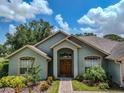 Inviting home facade showcasing a landscaped garden, arched entryway, and double front doors at 1902 Southern Dunes Blvd, Haines City, FL 33844