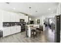 Bright, modern kitchen with white cabinets, stainless steel appliances, a breakfast bar with seating, and an open layout at 2980 Dayton Dr, Winter Haven, FL 33884