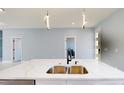 Close-up of a kitchen island with a double sink, quartz countertop, and contemporary pendant lights at 404 Miami Way, Kissimmee, FL 34759