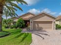 Inviting home exterior featuring a brick driveway, manicured lawn, and mature landscaping at 4327 Gullane Dr, Lake Wales, FL 33859