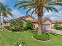 Charming home with a well-manicured lawn, mature palm trees, and a brick driveway under blue skies at 4327 Gullane Dr, Lake Wales, FL 33859
