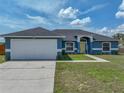 Charming blue single-story home featuring a well-manicured lawn and a bright yellow front door at 541 Hatchwood Dr, Haines City, FL 33844