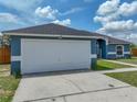 Side view of the single-story home's garage and partial view of the manicured front lawn at 541 Hatchwood Dr, Haines City, FL 33844
