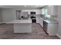 Kitchen showcasing an island, granite counters, stainless appliances, white cabinets, and wood-look floors at 628 Se Pine Ave, Fort Meade, FL 33841