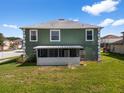 Back exterior view of a green two-story home with a screened in porch and green lawn at 1800 Emily Dr, Winter Haven, FL 33884