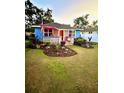 Charming home featuring blue siding, front yard landscaping, an American flag, and a cozy front porch at 195 E Vine St, Bartow, FL 33830