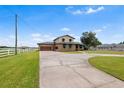 Two-story home with brick facade, attached garage, large driveway, and green awnings on a spacious lawn at 2731 State Road 557, Lake Alfred, FL 33850