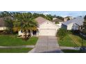 Inviting single-story home featuring a lush green lawn and a two-car garage, enhanced by mature palm trees at 3828 Eloise Estates Ct, Winter Haven, FL 33881