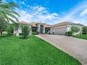 Well-maintained house with lush green lawn, brick driveway, and mature palm tree in a sunny setting at 4004 Sable Loop Dr, Lake Wales, FL 33859