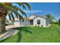 Single-story home showcasing a well-kept lawn, brick driveway, and lush tropical landscaping at 4175 Muirfield Loop, Lake Wales, FL 33859