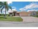 Beautiful single-story home with a palm tree, landscaped lawn, decorative fountain, and a brick-paved driveway leading to an attached garage at 5005 Pebble Beach Blvd, Winter Haven, FL 33884