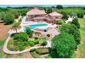 Aerial view of beautiful backyard with pool, water feature, covered patio and lush landscaping at 501 Adams Barn Rd, Auburndale, FL 33823