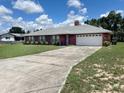 Single-story brick house with a long driveway, attached garage, and green lawn under a partly cloudy sky at 504 W 7Th St, Frostproof, FL 33843