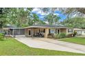 Well-maintained home with a carport, a screened-in porch, a driveway, and a lush green lawn at 616 Oriole Dr, Lakeland, FL 33803