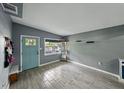 Bright living room featuring modern gray walls, light wood-look tile floors, and a striking blue front door at 1140 W Seminole Trl, Bartow, FL 33830