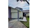 Two-story home featuring a two-car garage, small tiled walkway, and manicured front lawn at 12241 Augusta Woods Cir, Orlando, FL 32824