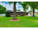 Well-maintained single-story home featuring a lush green lawn, mature trees, and a brick facade at 1491 Avenue F Ne, Winter Haven, FL 33881