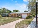 Traditional house featuring a covered porch, an attached garage, and a well-kept front yard, exuding classic suburban appeal at 1929 4Th Ne St, Winter Haven, FL 33881