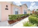 Close up of the front of the pink home featuring white shutters and lush landscaping at 263 Reserve Dr, Davenport, FL 33896
