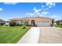 Inviting home with a spacious driveway leading to a two-car garage, complemented by lush lawn and mature landscaping at 413 Ruby Lake Pl, Winter Haven, FL 33884